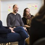 Male and female sitting on chairs smiling