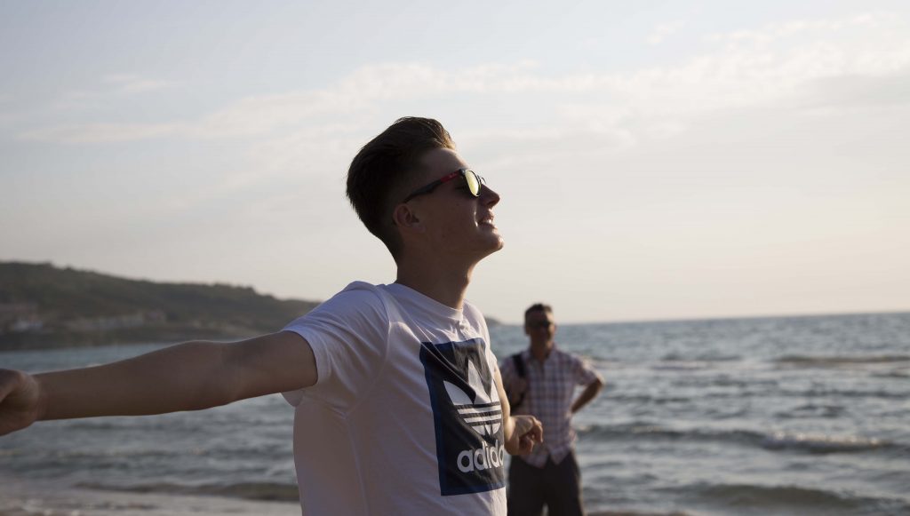 Teenagers arms open sea in background