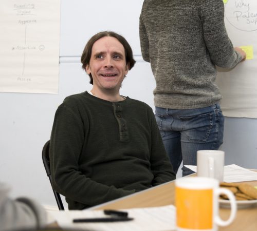 Male sitting at a table with a yellow mug on the table