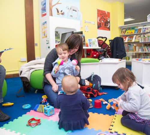 Female playing with children on the floor