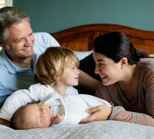 Male and female on a bed with a child and baby